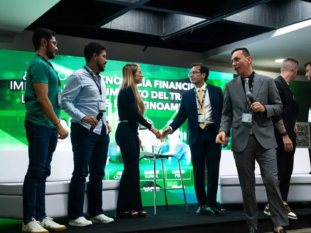 Um grupo de pessoas no palco iluminado de verde durante uma edição.