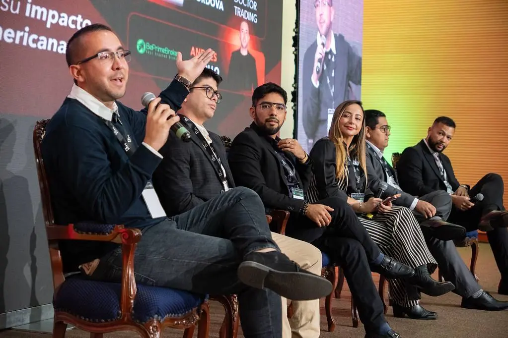 Painelistas sentados no palco durante uma conversa com microfone.